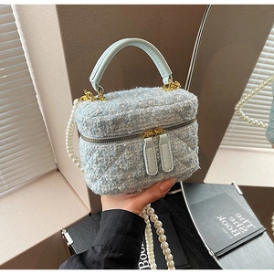 Détail du sac seau en tweed avec motif matelassé, chaîne en perles et fermetures dorées