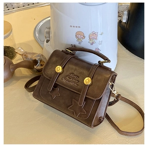 Detailed macro view of vintage brown crossbody bag with star patches and embossed text
