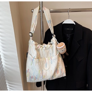 Detail of white jacquard tote bag with wavy embroidery, drawstring and coffee cup charm