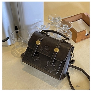 Detail of dark chocolate square bag with gold buckle and star-shaped stitching on leather