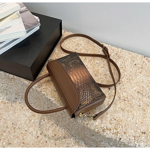 Detailed view of brown faux leather bag with snake skin texture and gold hardware