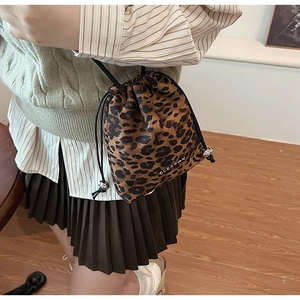 Détail du sac seau à imprimé léopard avec cordon de serrage et plaque de marque argentée