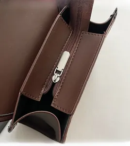 Detailed close-up of the smooth silver zipper and neat stitching on a brown leather backpack