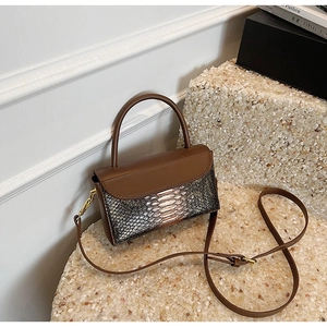 Detail of vintage brown shoulder bag with mixed faux snakeskin texture and gold hardware