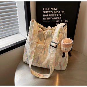 Quilted tote bag detail with colorful embroidery, drawstring closure and coffee cup charm