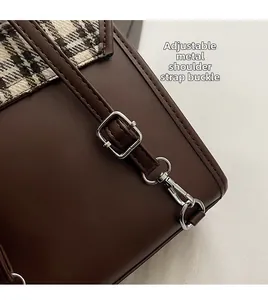 Detail of adjustable metal hardware buckle and strap on brown plaid contrast backpack