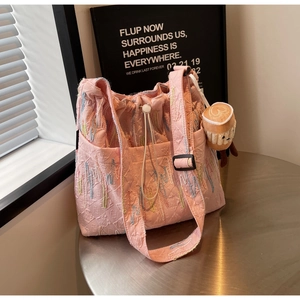 Close-up of pink quilted tote bag with colorful wave embroidery and plush cup charm