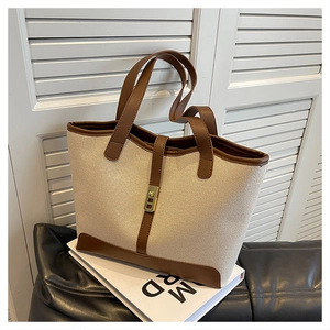 Detail of canvas tote bag with brown leather trim and golden metal lock on book