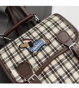 Detail of dachshund embroidery and brown checkered fabric on a vintage backpack