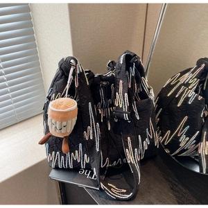 Detail of black tote bag with colorful heartline embroidery and a coffee cup plush charm