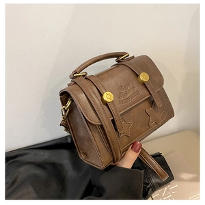 Close-up of brown vintage crossbody bag with star patches and golden buckles details