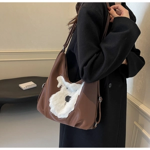 Détail d'un sac à bandoulière en cuir marron avec broderie de chien en fausse fourrure