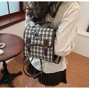 Detail of a vintage plaid mini backpack with leather straps and dachshund embroidery