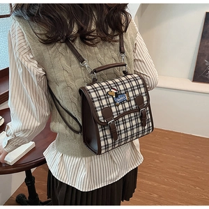 Detailed side view of a vintage plaid backpack with a cute dog embroidery in a cafe
