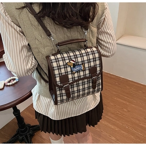 Detail of checkered backpack with dachshund embroidery worn by a model in warm indoor setting
