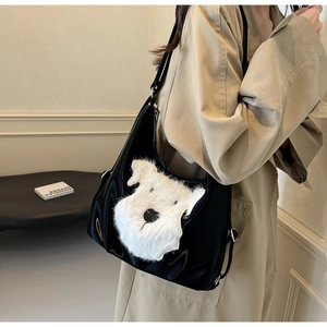 Détail d'un sac cabas noir brillant avec une broderie de chien en peluche blanche