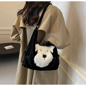 Détail d'un sac bandoulière noir avec broderie chien blanc porté sur un trench-coat kaki