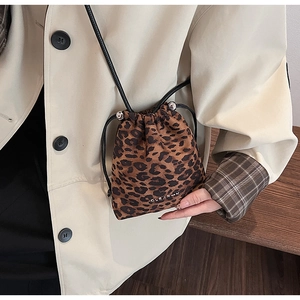 Détail d'un sac seau à imprimé léopard avec cordon et plaque logo métallique