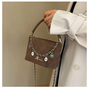 Detail of coffee brown quilted suede handbag with heart charms and gold chain strap