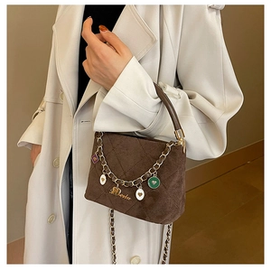Detail of frosted brown bucket bag featuring gold chain and colorful enamel pendants
