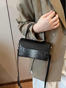 Vintage black crocodile embossed handbag with gold hardware shown on a stylish model