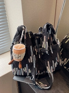 Quilted black nylon tote bag with colorful wave embroidery and cute plush coffee cup charm
