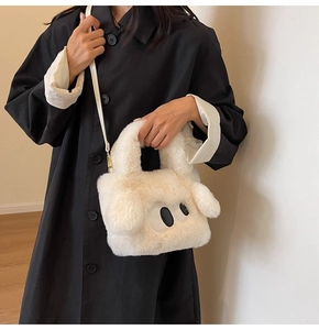 Nahaufnahme der weißen Plüschtasche mit Comic-Augen auf einem schwarzen Wintermantel