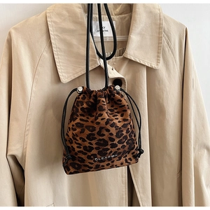 Détail du sac seau à imprimé léopard avec cordon ajustable sur un trench-coat beige