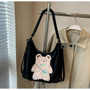 Détail de la broderie ours en peluche marron sur un sac à bandoulière en nylon noir