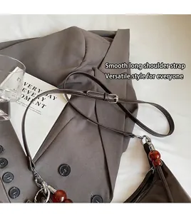 Detail of adjustable leather strap and brown bead pendant on a stylish shoulder bag