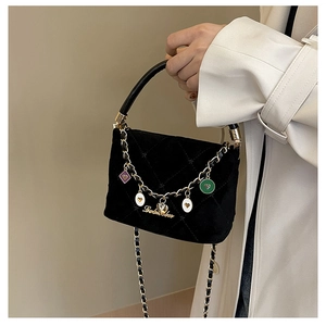 Close-up of black quilted suede bucket bag with gold heart charms and chain strap detail