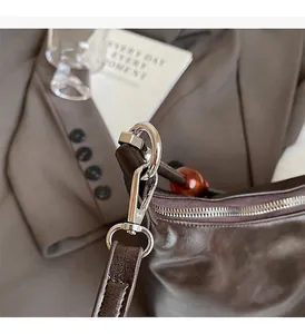 Macro detail of silver-polished metal zipper and hooks on a dark brown leather handbag