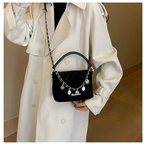 Close-up of black quilted suede handbag with colorful enamel charms on leather chain