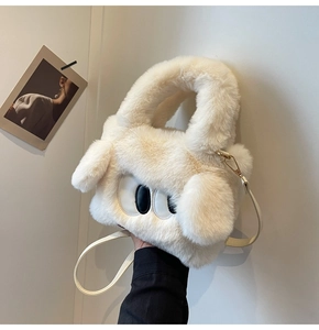 Detail der cremefarbenen Plüschtasche mit Cartoon-Augenstickerei und Goldkarabinern