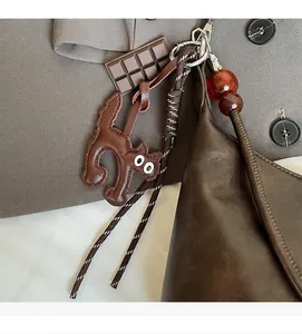 Detailed view of a brown leather cat charm with resin accents on a shoulder bag