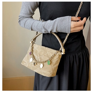 Detail of khaki suede bucket bag with quilted patterns and colorful heart charms