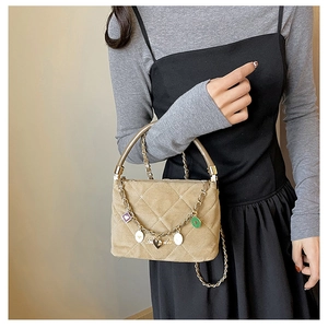 Detail view of khaki quilted handbag with decorative metal chain and colorful enamel charms