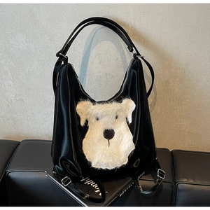 Détail d'un sac à dos en cuir noir avec broderie chien en peluche blanche et finitions argentées
