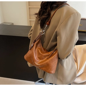 Detail of a brown vintage leather shoulder bag with amber beads and circular metal lock