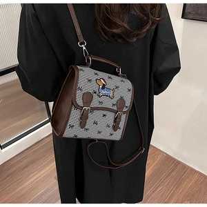 Detail of crossbody bag featuring houndstooth pattern and puppy embroidery on model