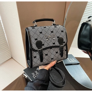 Detail of herringbone fabric handbag featuring black bow patterns and metal buckle