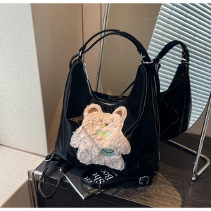 Détail du sac cabas noir brillant avec ornement d'ours en peluche et bandoulière