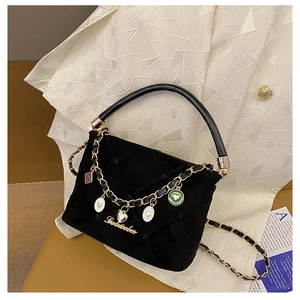 Detail of black velvet quilted handbag with gold chain strap and heart charms