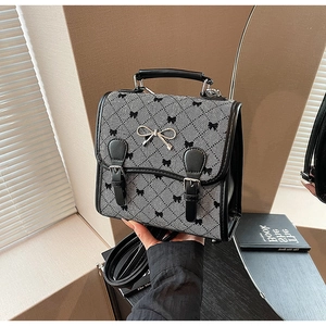 Detailed view of the houndstooth fabric texture and metal bow clasp on the retro handbag