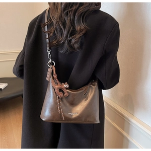 Detail of dark brown hobo bag with cartoon cat charm and chocolate bar pendant