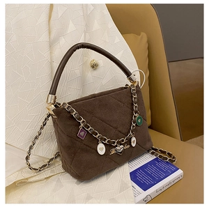 Detail of brown quilted suede bucket bag featuring colorful heart charms and gold chain