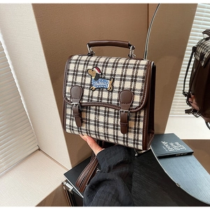 Detail of vintage plaid backpack featuring an embroidered dachshund with a red hat