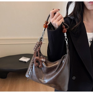 Detail of dark brown leather underarm bag with amber beads and cute cat charm