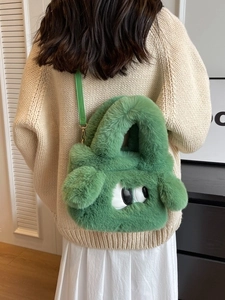 Süße grüne Plüschtasche mit Cartoon Augen Design am Modell für modischen Herbst-Look