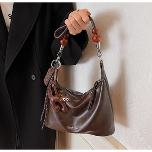 Detail of dark brown leather hobo bag with amber beads and chocolate charm decoration